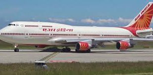 A large Air India Boeing 747 passenger jet sits on the runway at an airport, with the words "Air India" visible on the side of the fuselage.