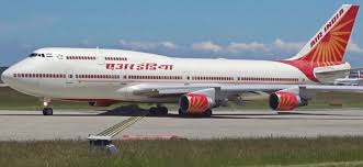 A large Air India Boeing 747 passenger jet sits on the runway at an airport, with the words "Air India" visible on the side of the fuselage.